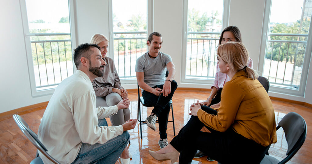 Un grupo de adultos se sientan en círculo mientras hablan.