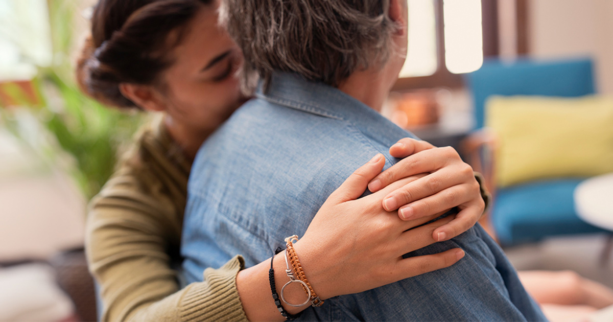 A woman embraces the person sitting next to her.